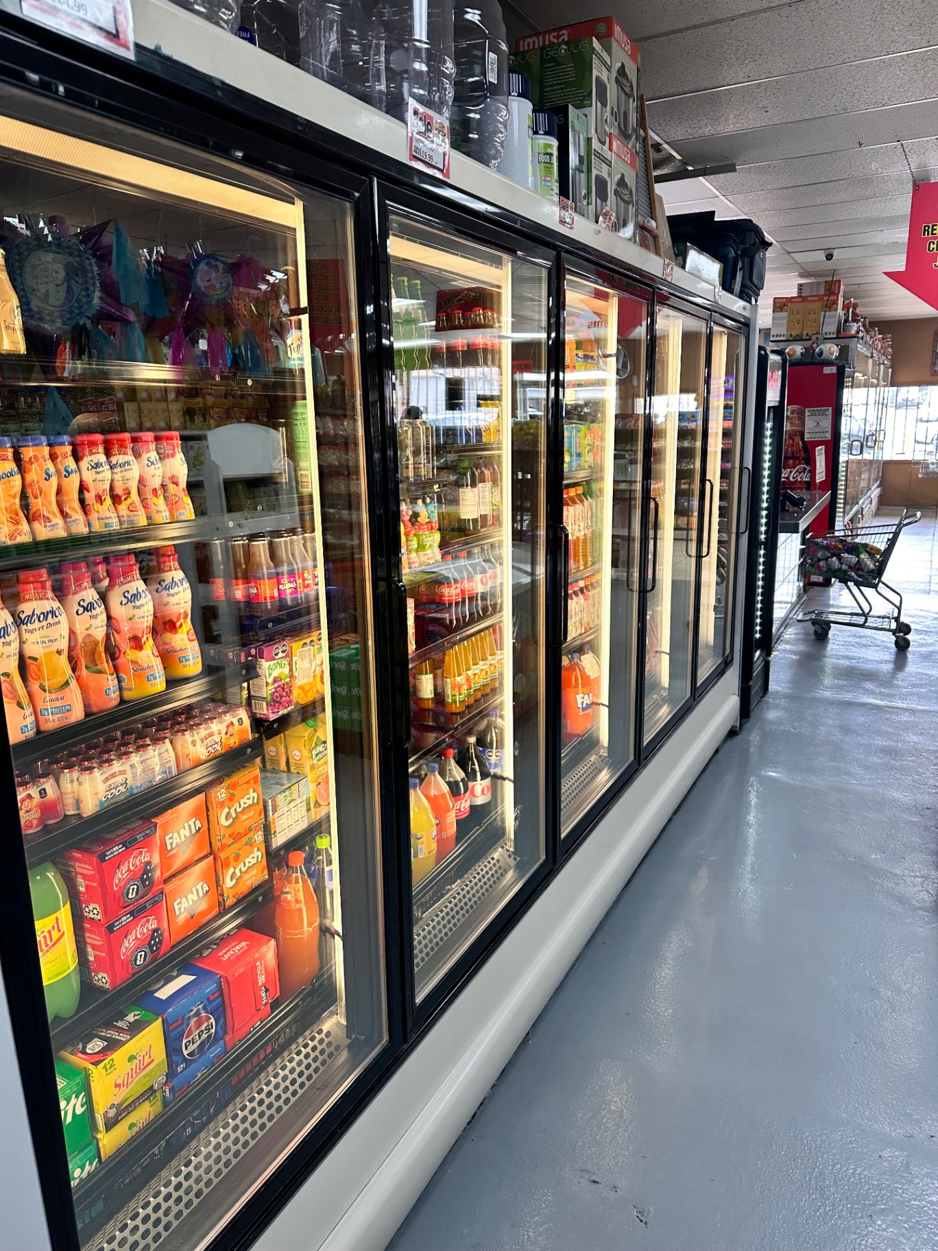 Wall of beverage coolers stocked with Mexican sodas, jugos, and Saborín yogurt drinks