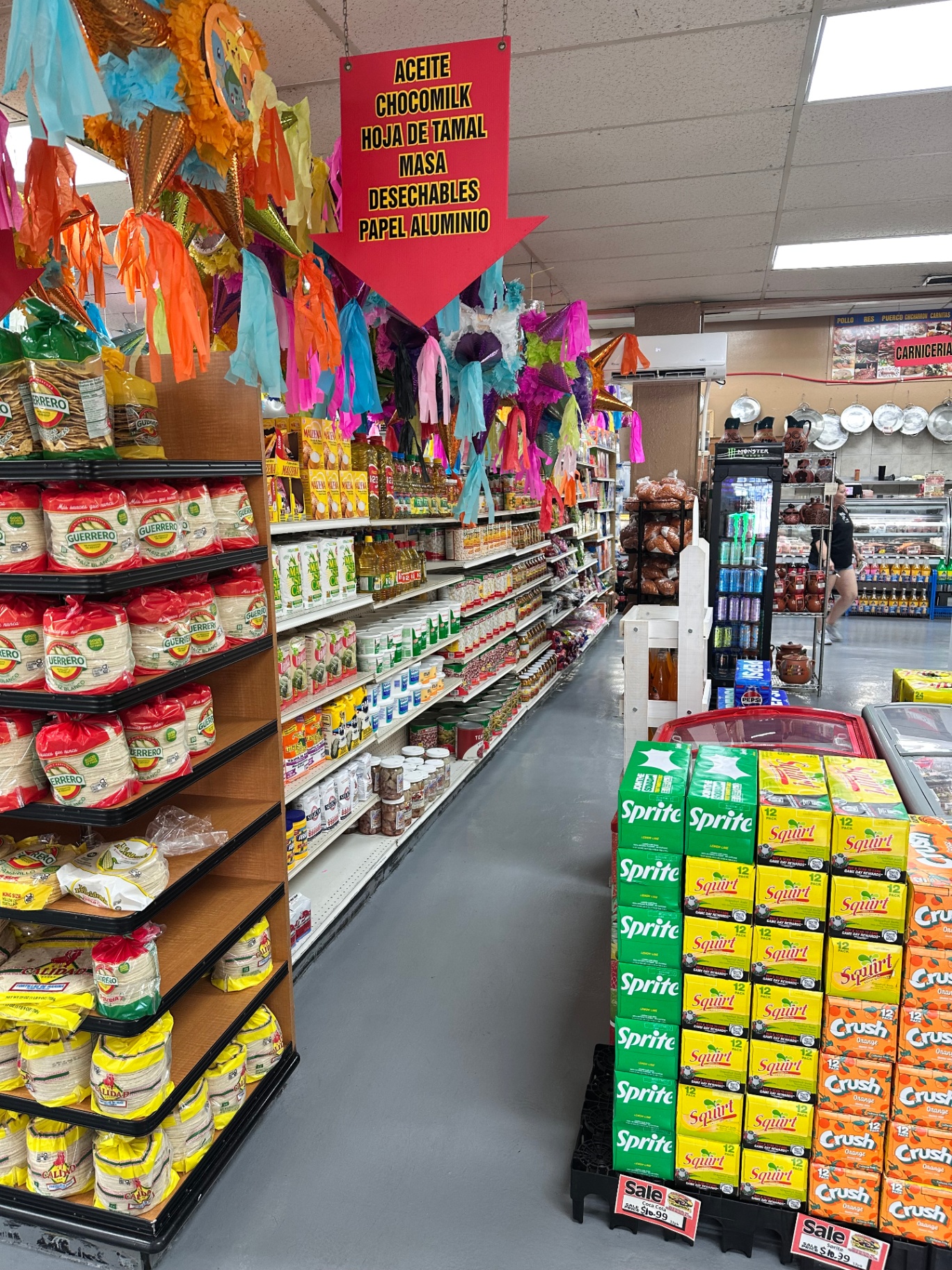 Los Amigos mercado aisle stocked with piñatas and pantry staples